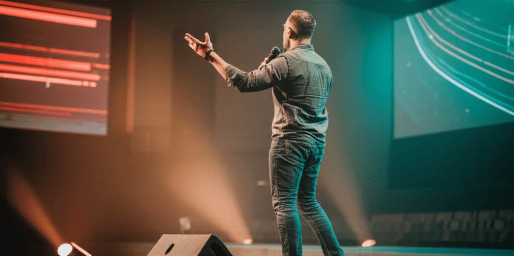 Modern church stage during sermon with pastor speaking, contemporary worship environment with LED screens and warm stage lighting